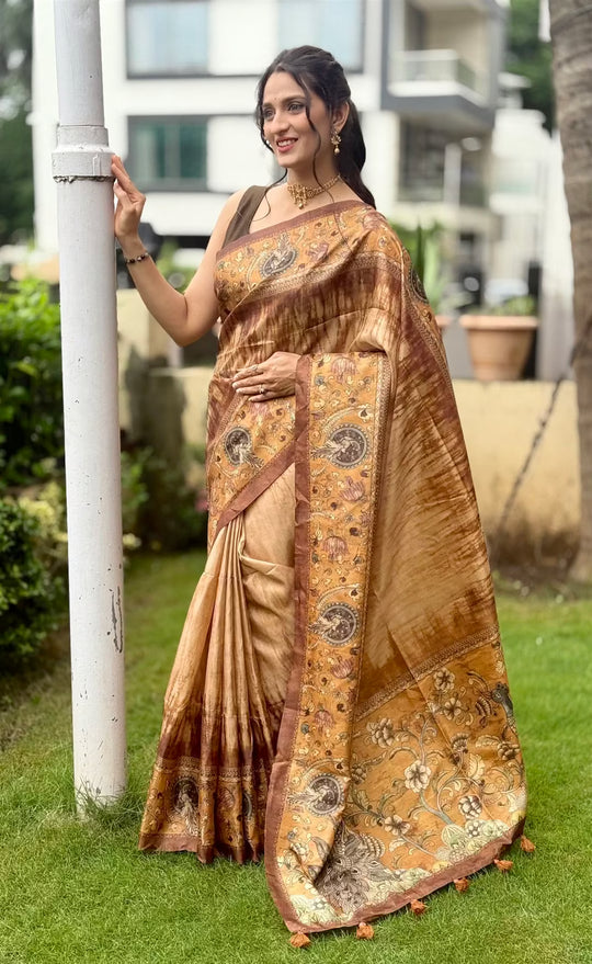 Woman wearing peacock pallu printed saree in gold and deep brown tones.