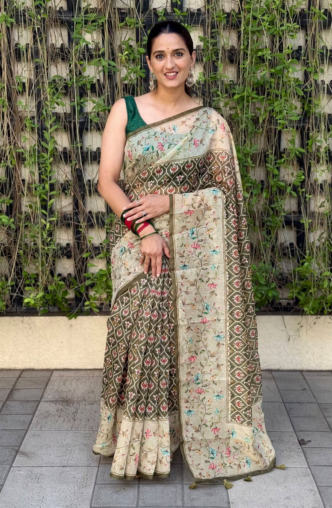 Woman wearing Mehndi Patola with Beige Floral Print Silk Saree with Natural Green Background.