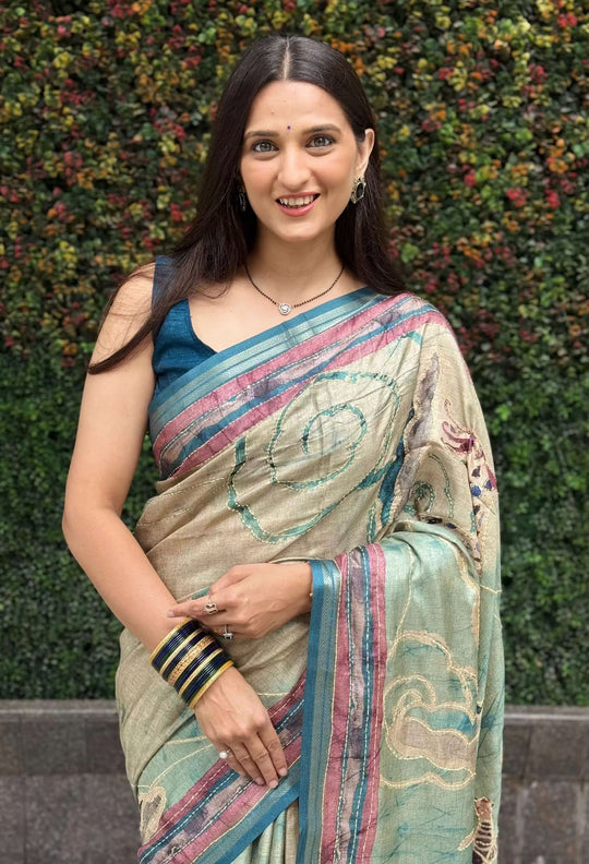 Woman wearing a Cream & Cyan Katha Work Kalamkari Dola Silk Saree with Zari Border.