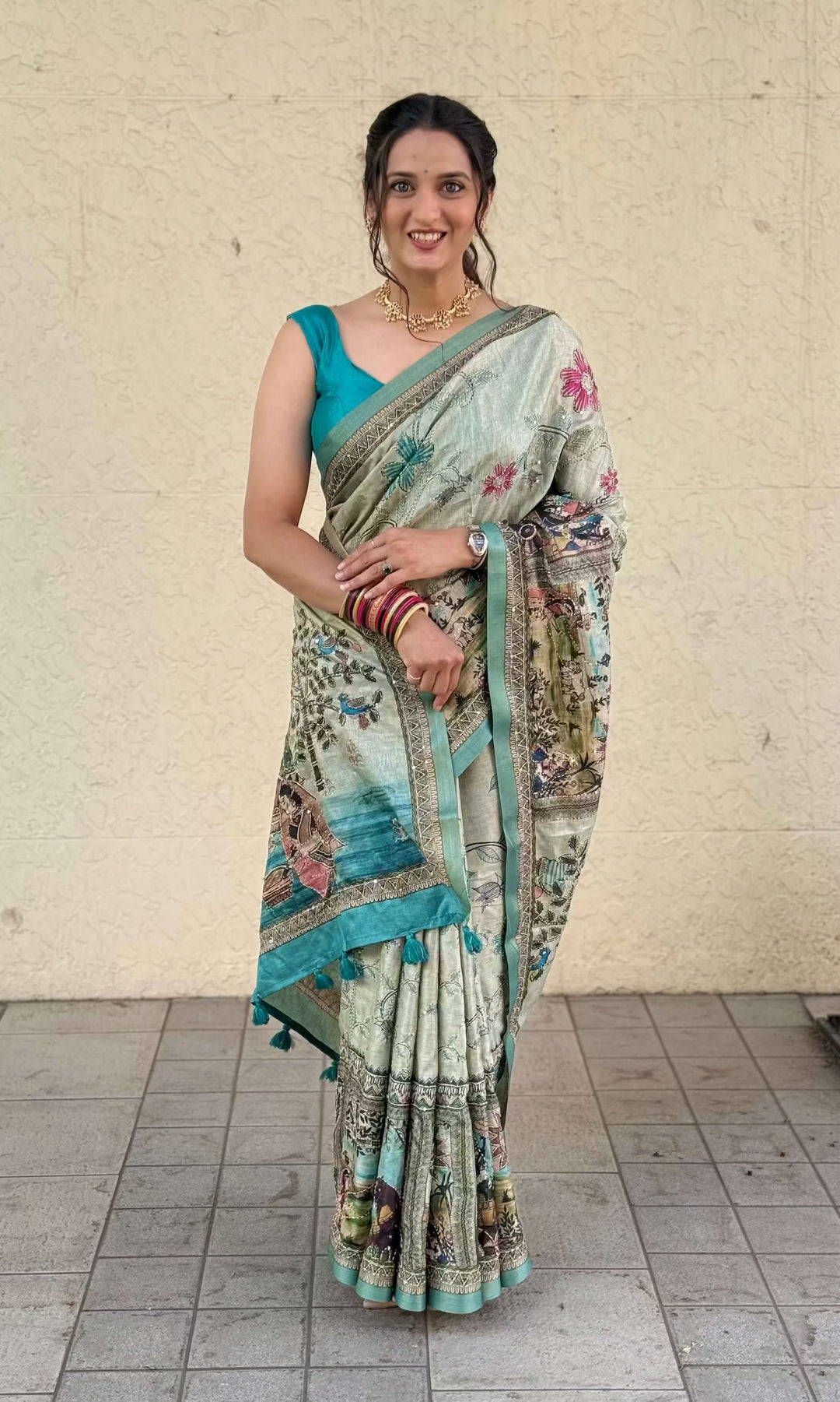 Woman wearing a Katha saree with a blue blouse against a beige wall.