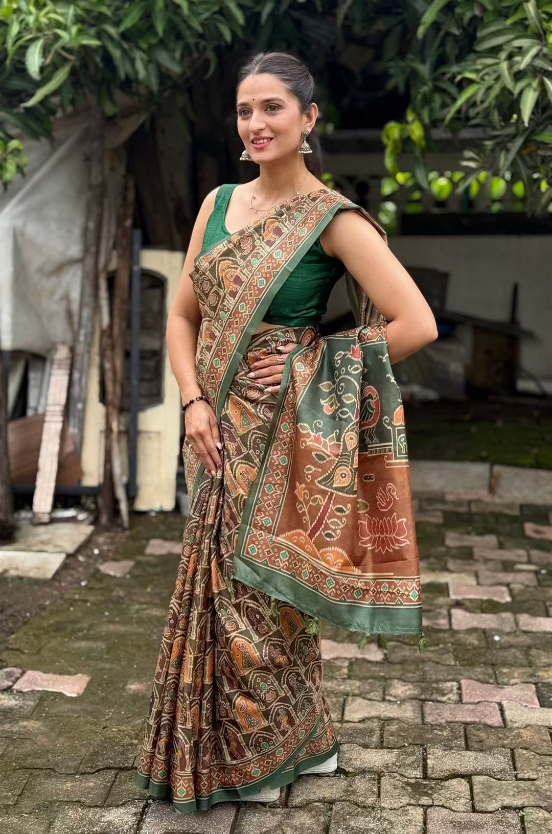 Woman wearing a Green & Brown pallu with Peacock and Temple style motifs.