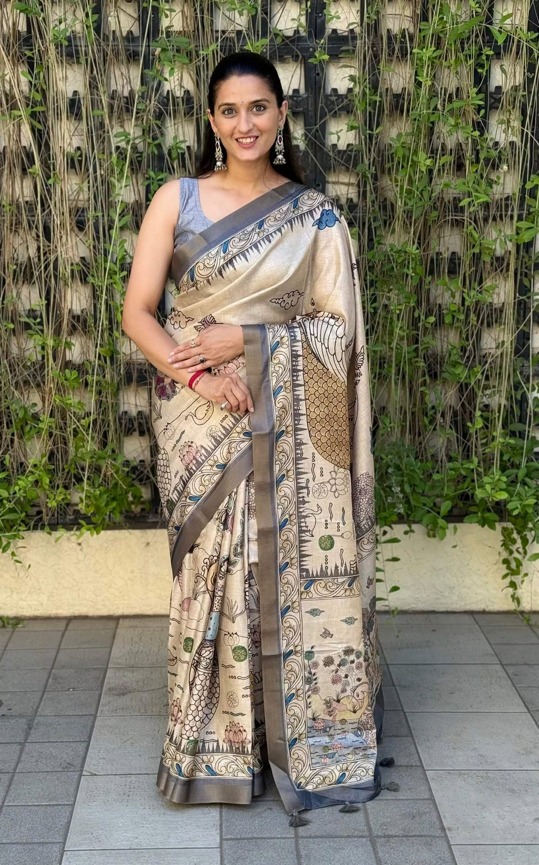 Woman wearing a traditional saree in Ash Grey, standing against a natural background.