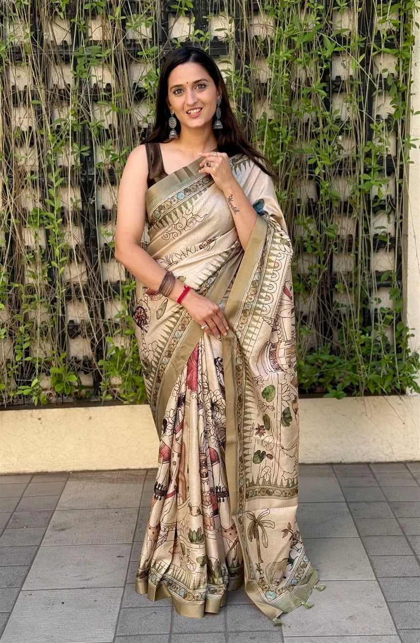 Woman in a Beige saree with a Kalamkari pattern standing against a textured wall.