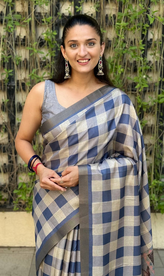 Woman wearing a Steel Blue and White checkered saree with a Zari border against a natural background.