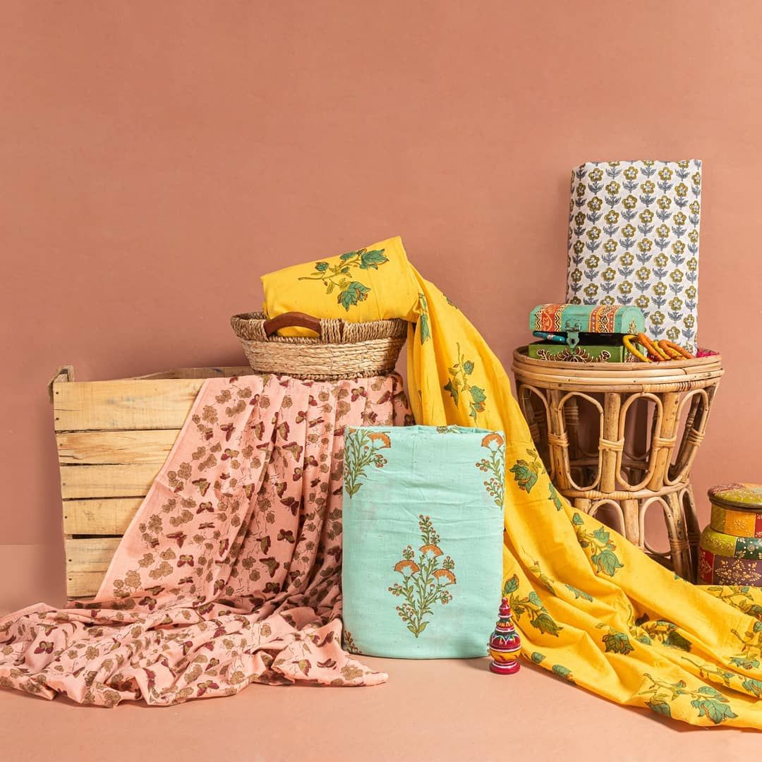 Colorful printed saree and decorative items on a plain background