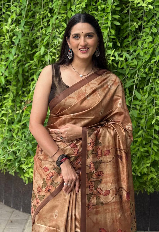 A women wearing copper color saree in kalamkari lotus print with brown border.
