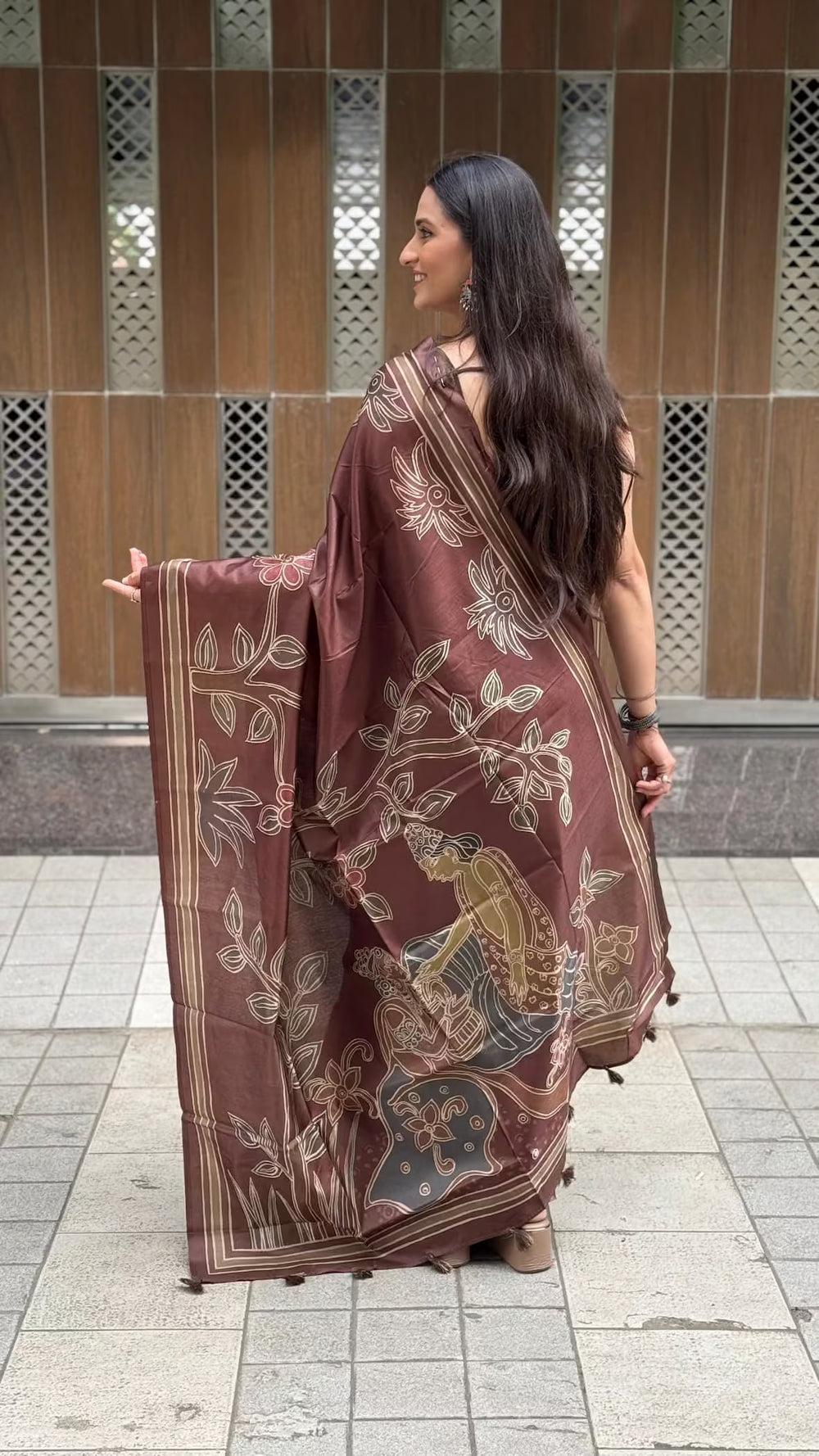 A woman wearing a brown printed saree with floral and traditional motifs by Ethnic Today.