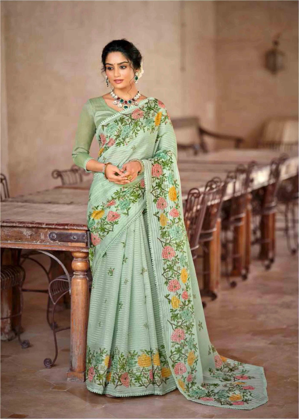 Woman wearing a light green saree with floral patterns.