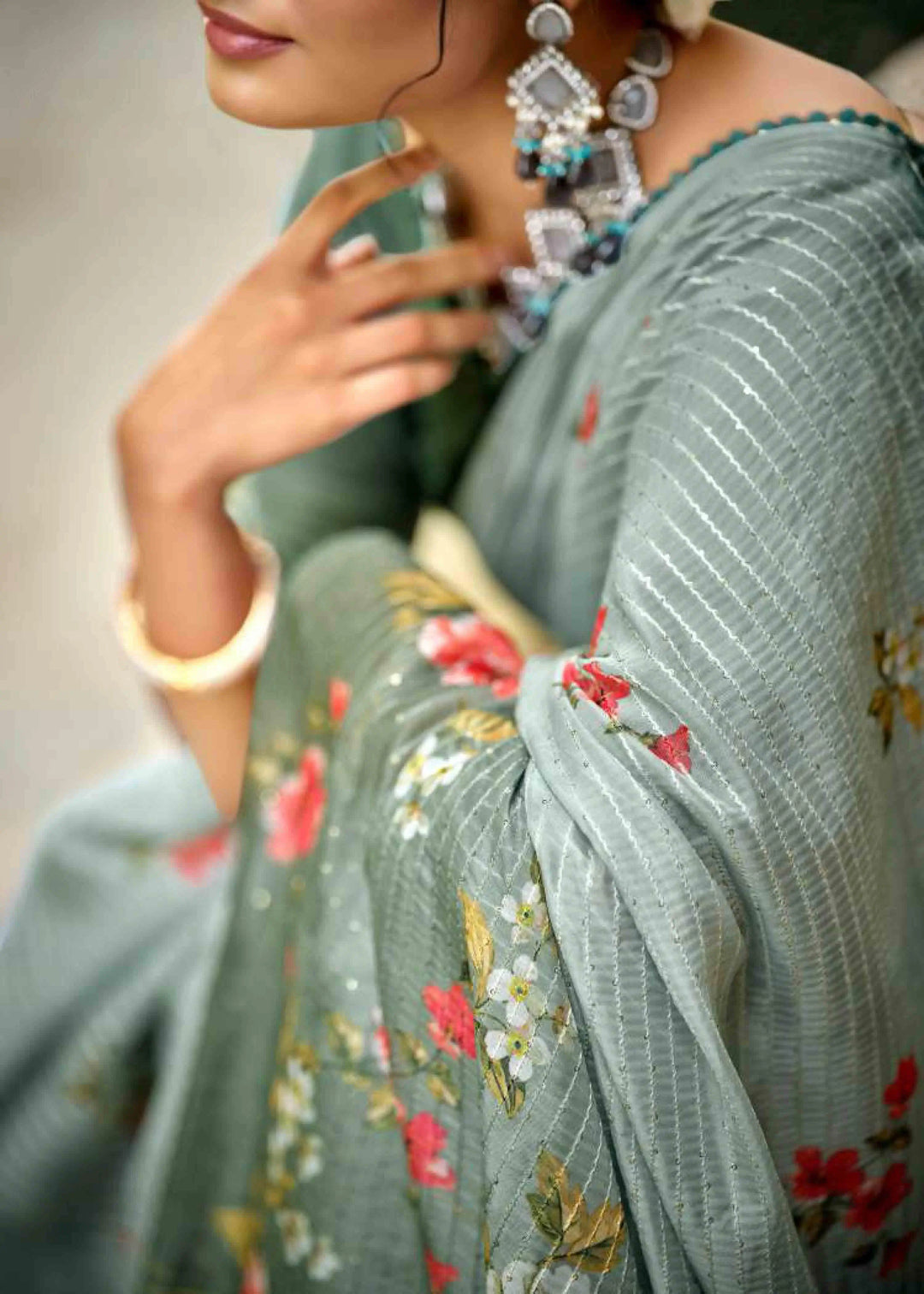 Woman wearing a light Grey saree with floral patterns.